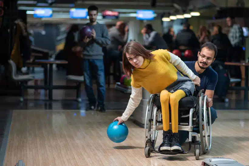 Moniteur éducateur en activité bowling avec un public atteint de handicap physique